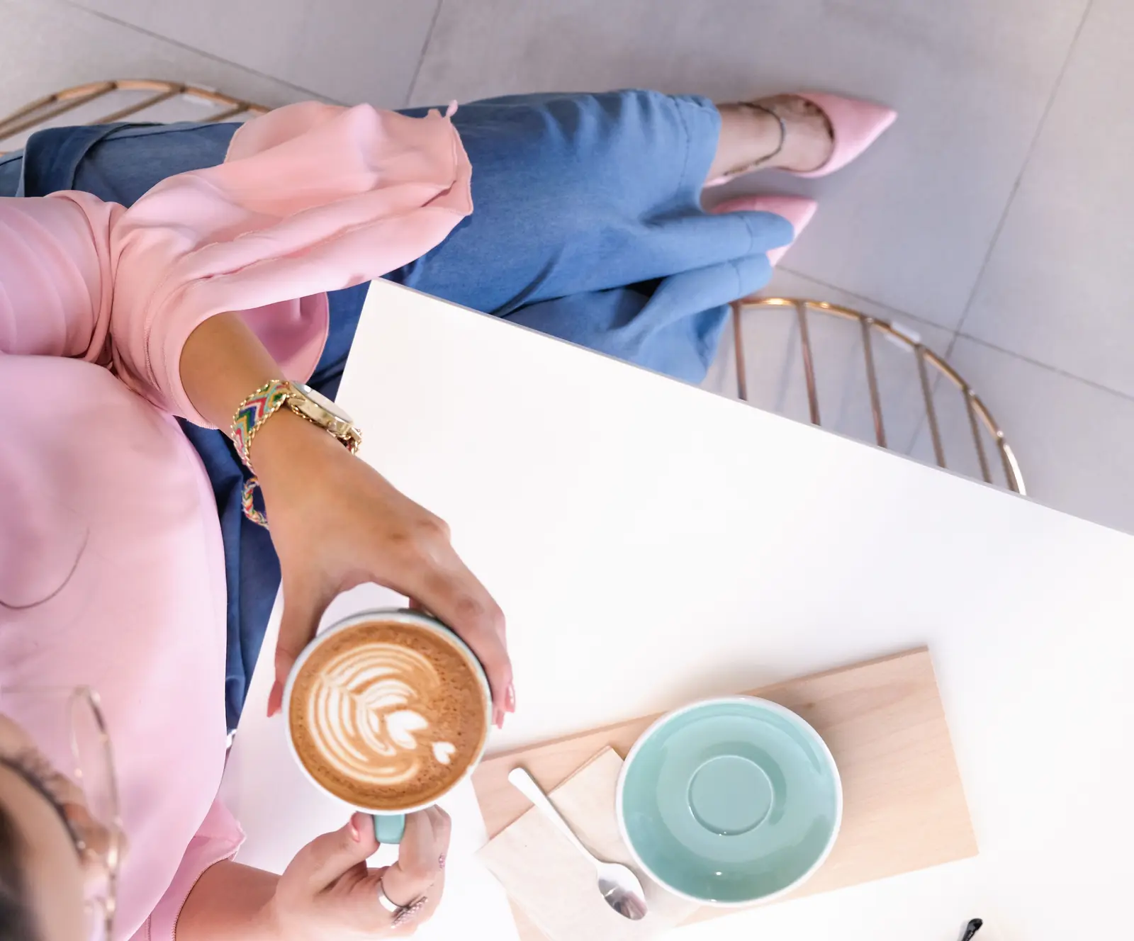 The best cafés to work from in Dubai Stylish woman enjoying a cappuccino with latte art at a chic Dubai cafe.