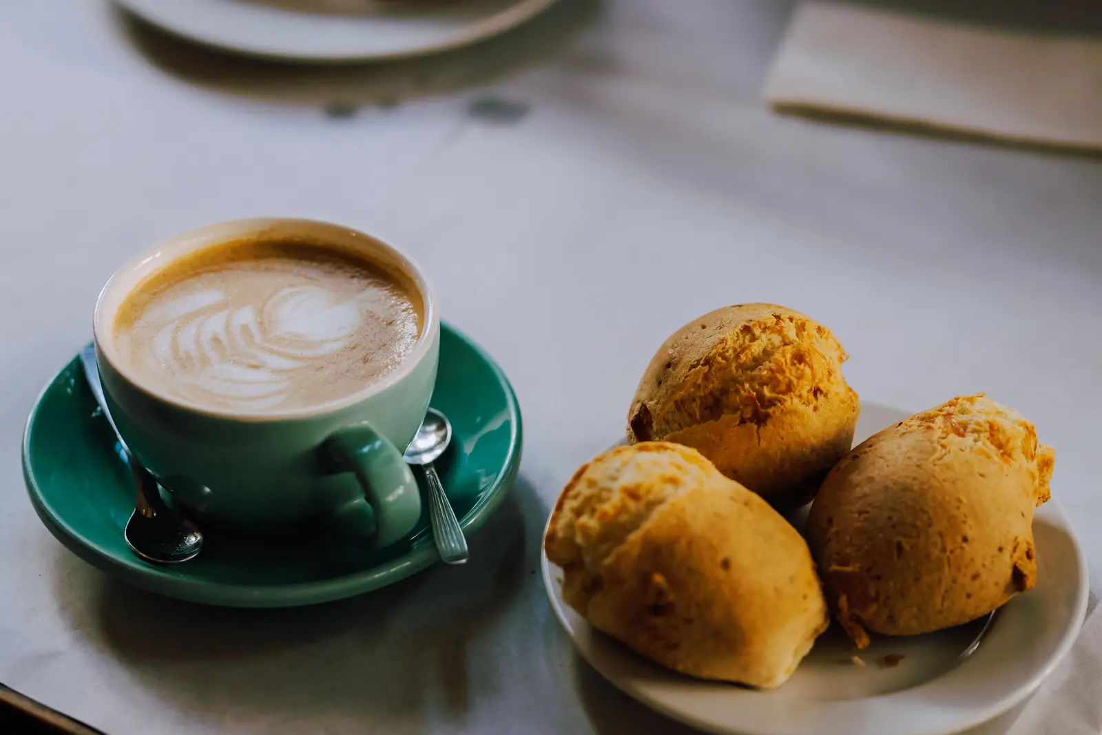 A cozy morning scene featuring a latte with artful foam and freshly baked buns in Buenos Aires.
