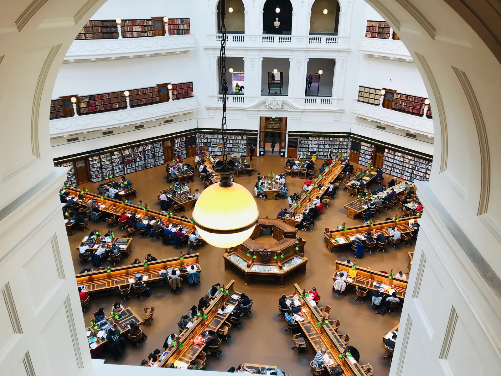A vibrant, high-angle view of the bustling reading room at State Library Victoria in Melbourne.