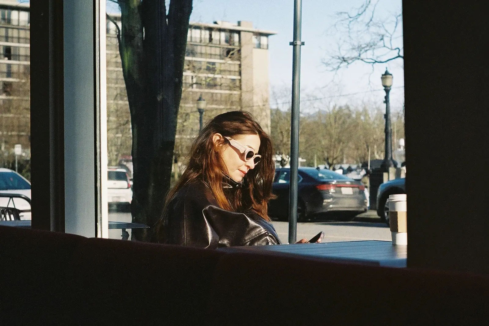 The best cafés to work from in Vancouver Woman enjoying morning coffee and sunlight in a Vancouver cafe, embracing a modern urban lifestyle.