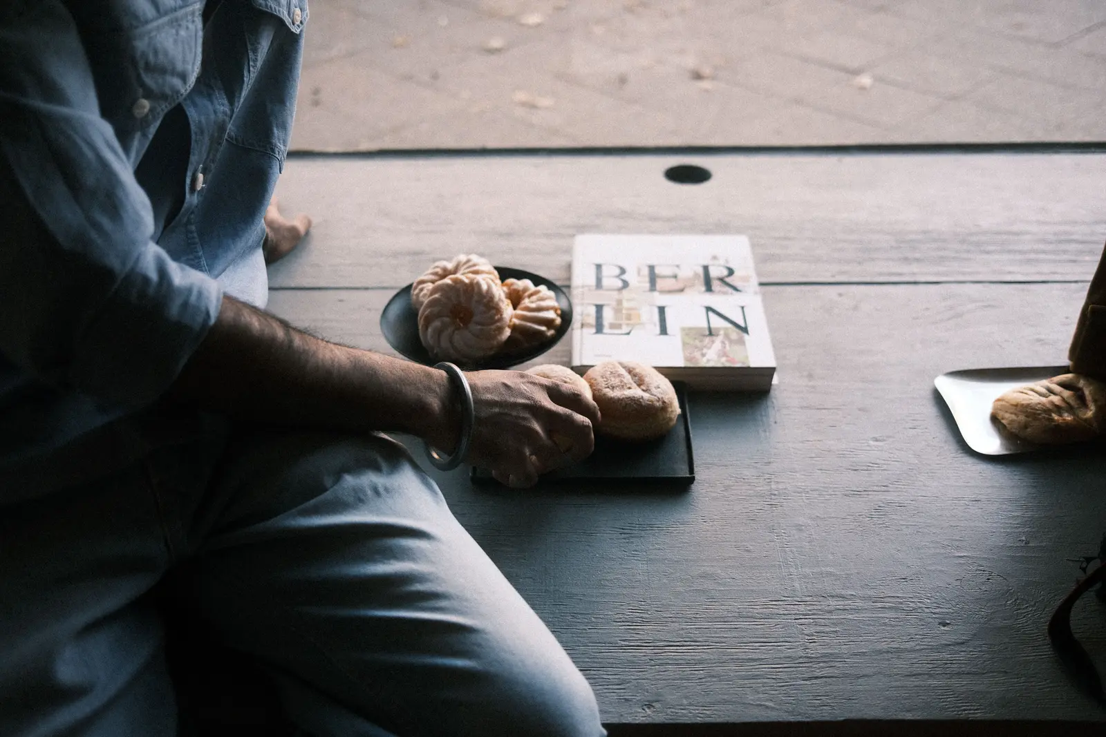 The best cafés to work from in Berlin Casual scene with pastries and a Berlin book on a wooden table.