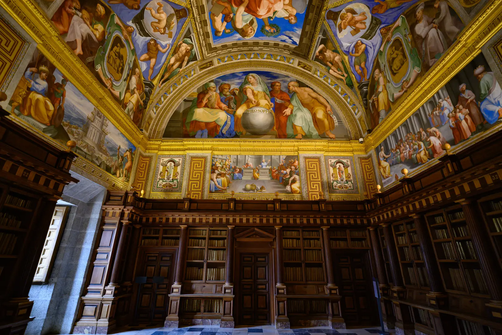 The best libraries to work and study in Madrid Intricate artwork adorns the ceiling of a grand library in Madrid, Spain.