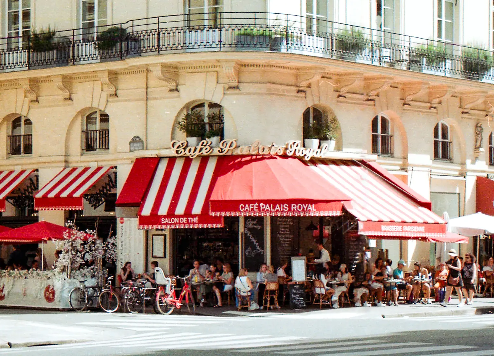 The best cafés to work from in Paris A bustling scene at Café Palais Royal in Paris with patrons enjoying a sunny day.