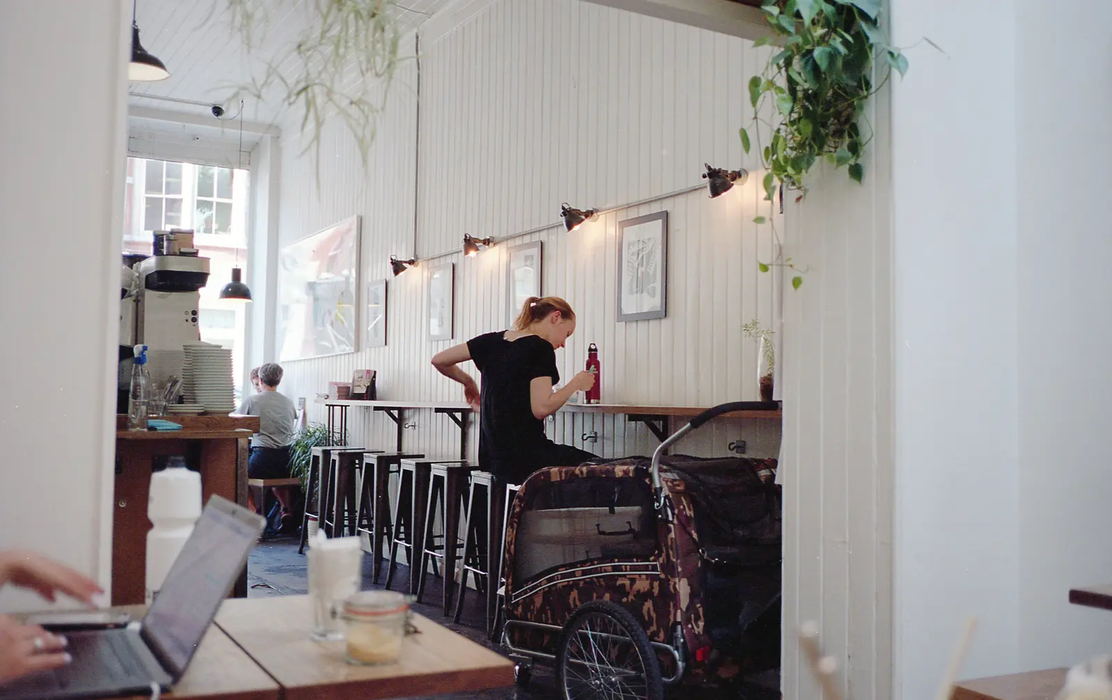 The best cafés to work from in London A calm London café scene with people working and relaxing, featuring white walls and indoor plants.