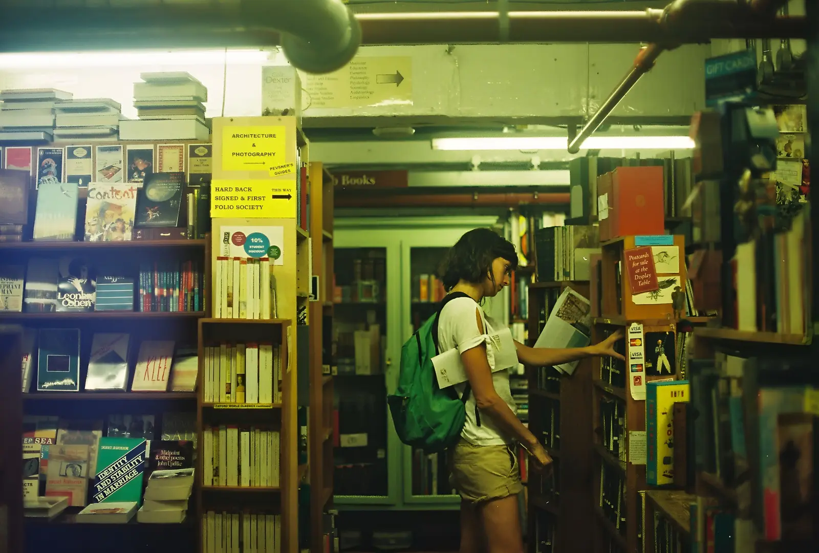 The best places to study in London, according to Reddit A woman explores a cozy London library, engrossed in book selection.