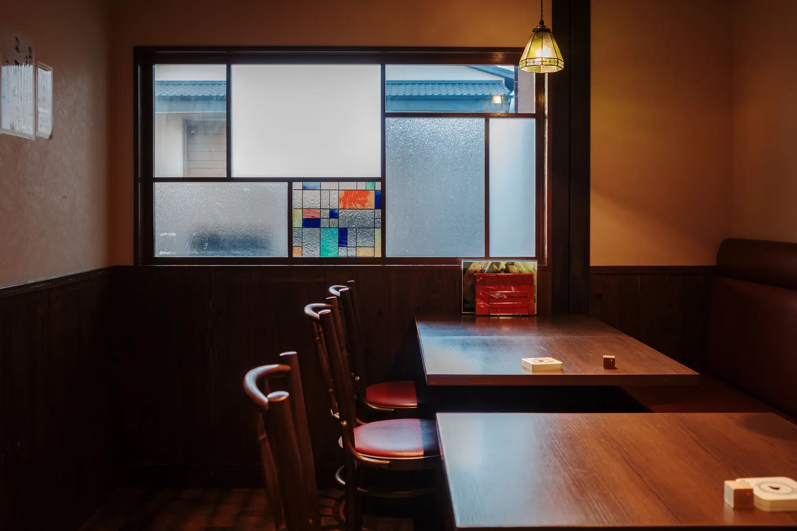 The best cafés to work from in Kyoto Warm and inviting Kyoto café interior featuring wooden furniture and stained glass detail.