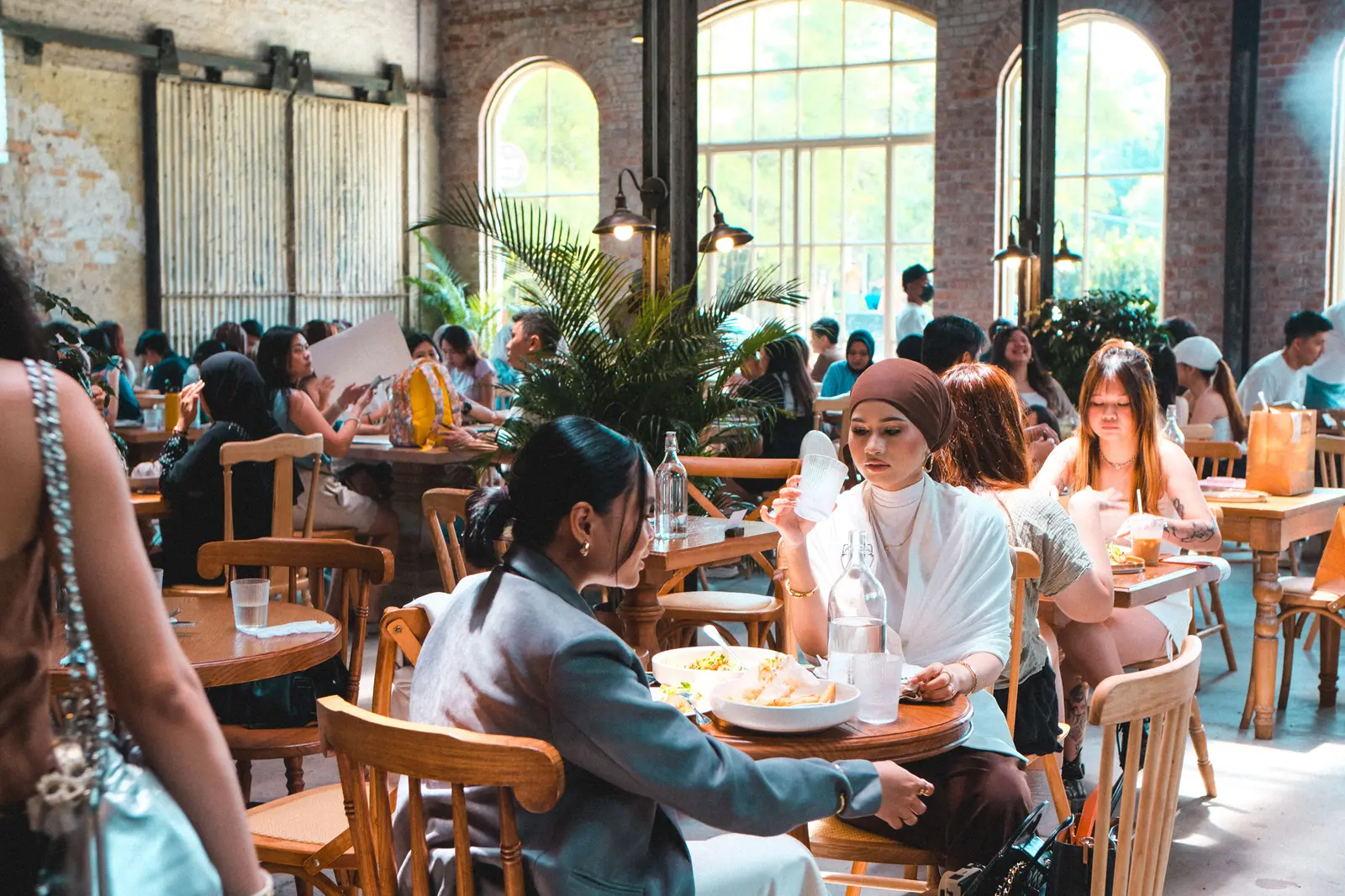 Capture of a bustling café scene in Kuala Lumpur, showcasing diverse interactions and vibrant dining atmosphere.