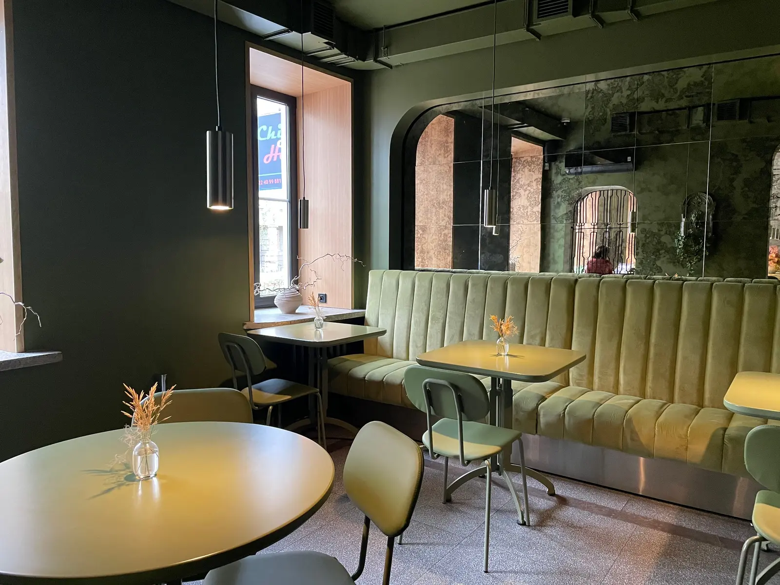 The best cafés to work from in Warsaw Chic cafe interior in Warsaw featuring green velvet seating and minimalist decor.