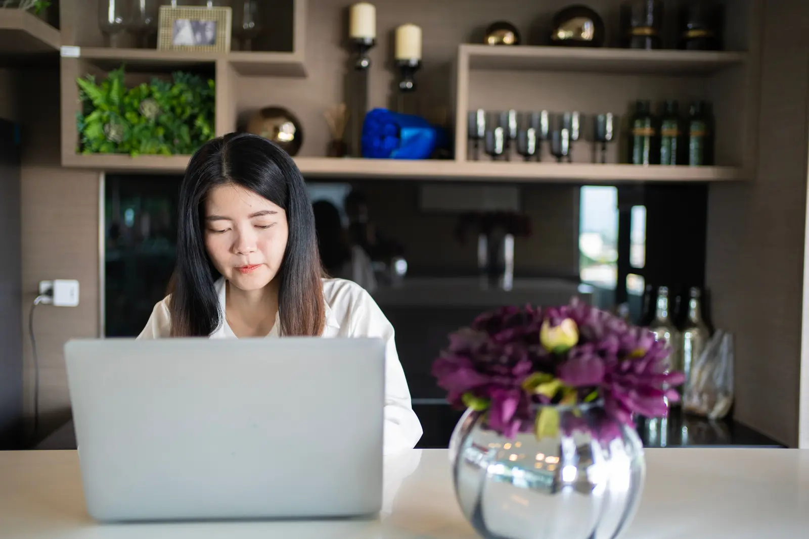 The best coworking spaces in Bangkok Young Asian woman working on her laptop in a modern, stylish home office in Bangkok.