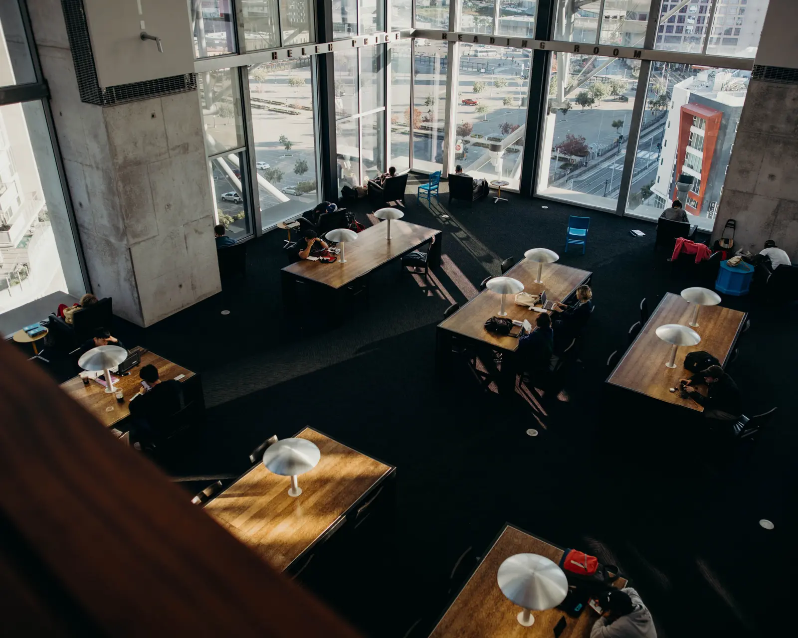 The best places to study in San Diego Bird's-eye view of a modern library with tables and people studying by large windows in San Diego, CA.