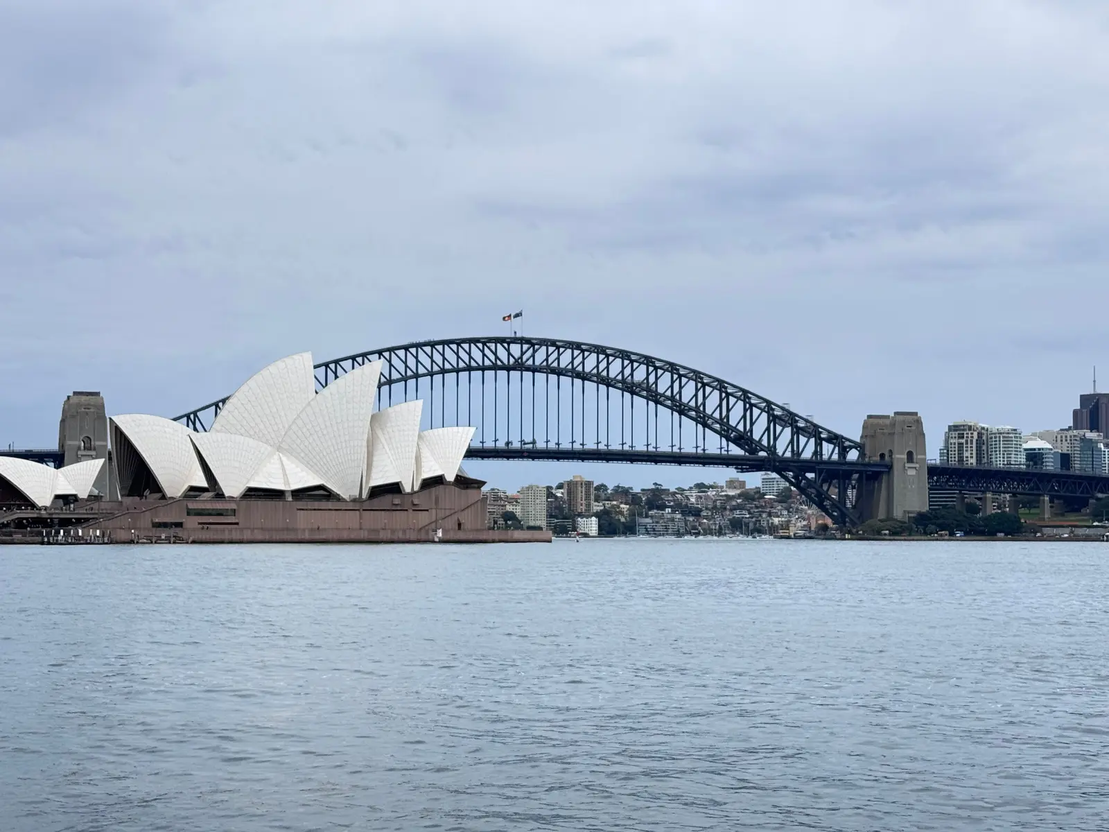 A vibrant view of Sydney Harbour Bridge with Luna Park and sailboats highlighting the iconic skyline.