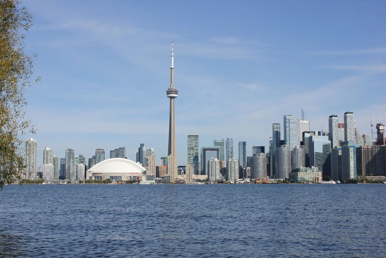 Beautiful sunset view of Toronto skyline with CN Tower and city lights reflecting on the lake.