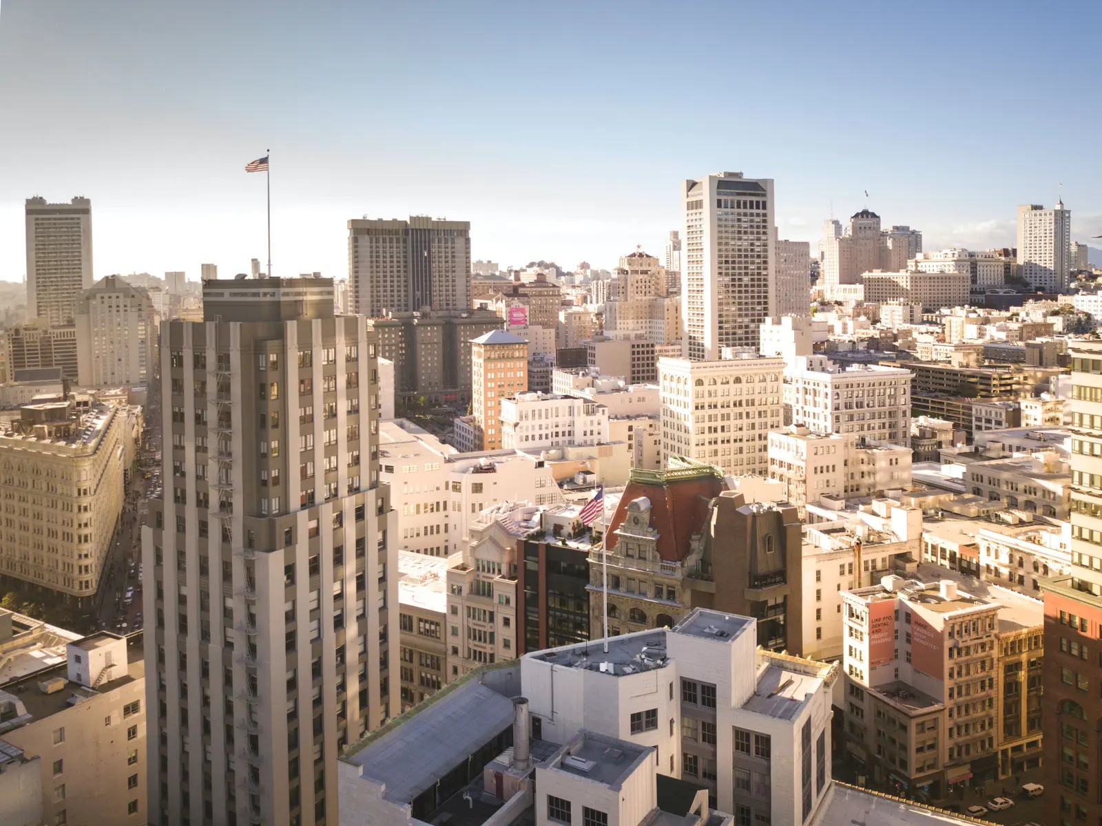 Stunning aerial view of San Francisco's skyline, featuring the iconic Bay Bridge under a bright sky.