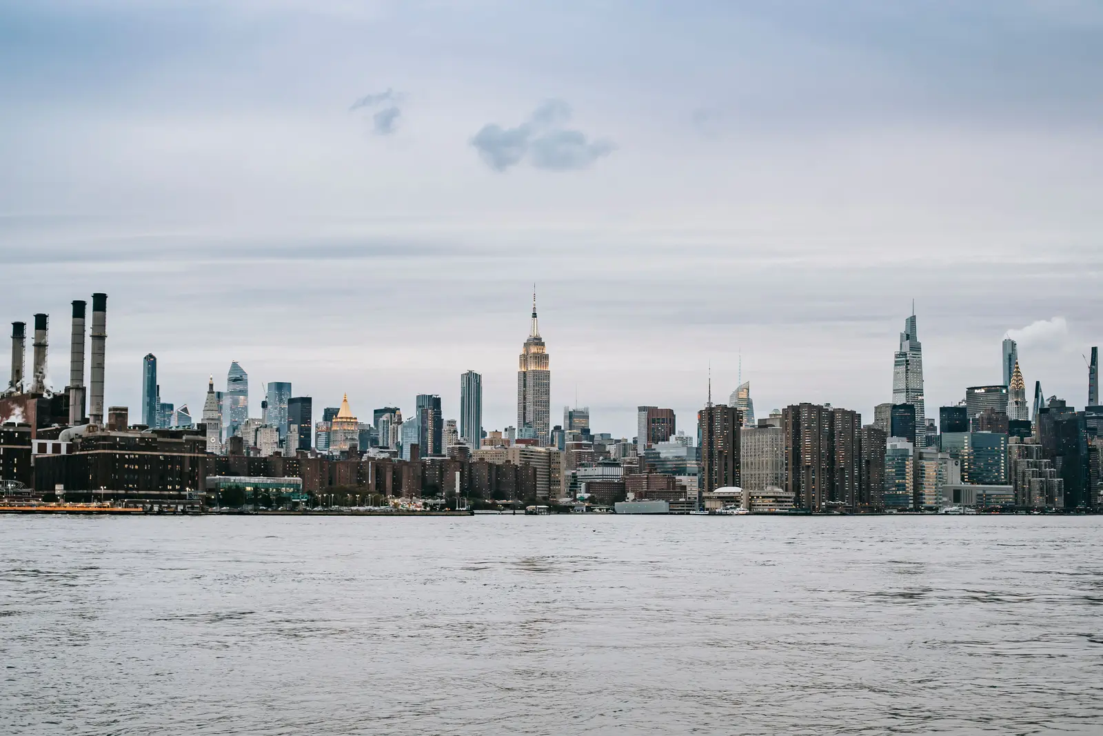 A dramatic view of the skyscrapers of New York City captured from the Brooklyn Bridge.
